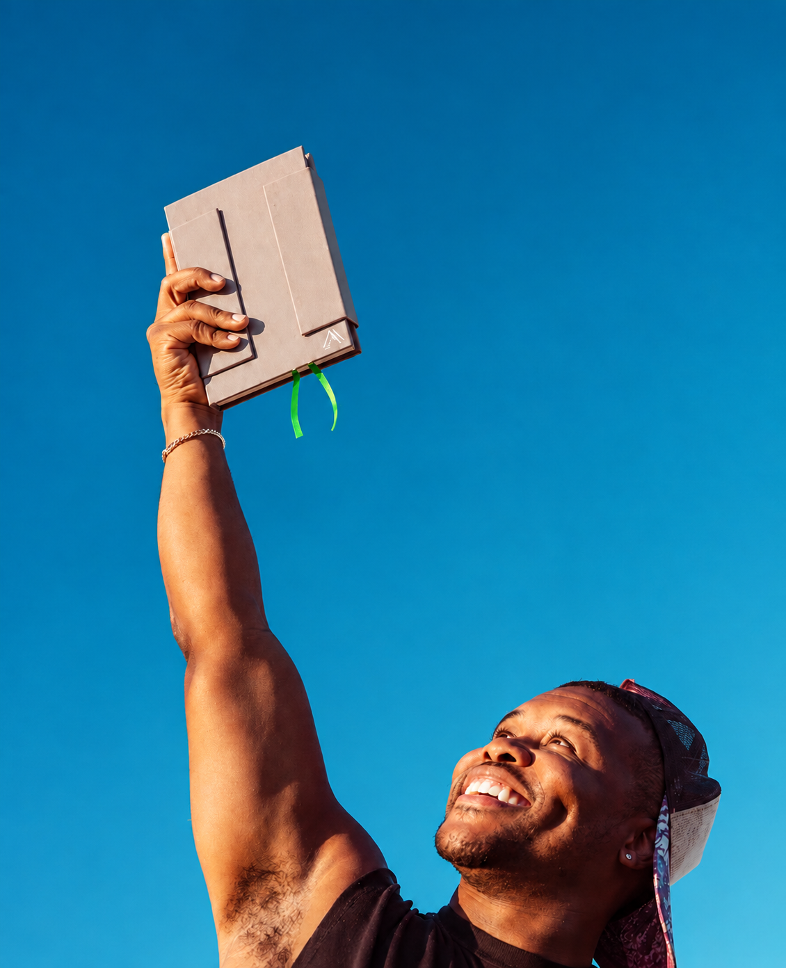 Aviante Atelier Series 001 sketchbook held overhead against a vivid blue sky